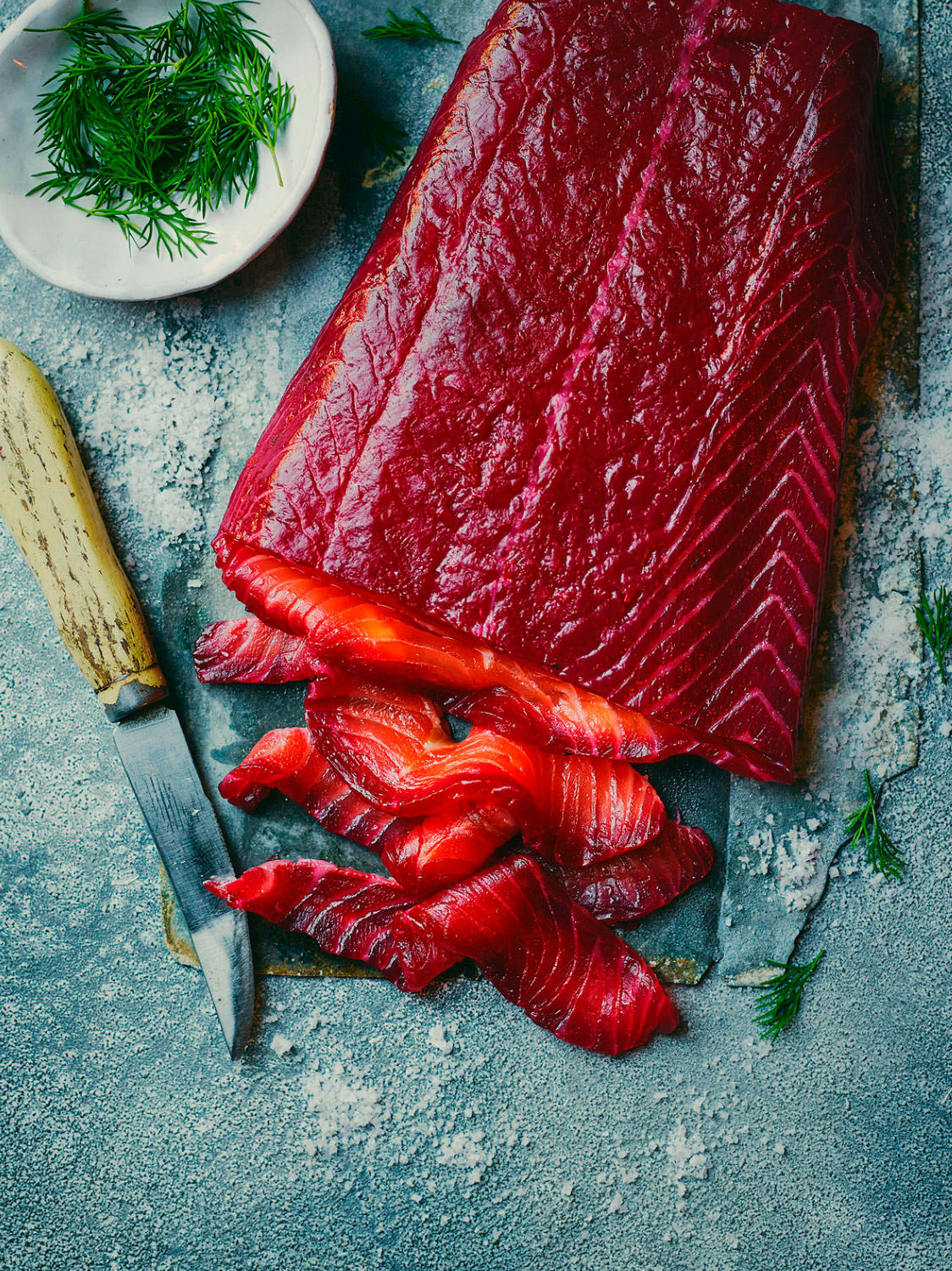 Beetroot Salmon Gravlax - purple salmon fillet sliced served with dill herbs   