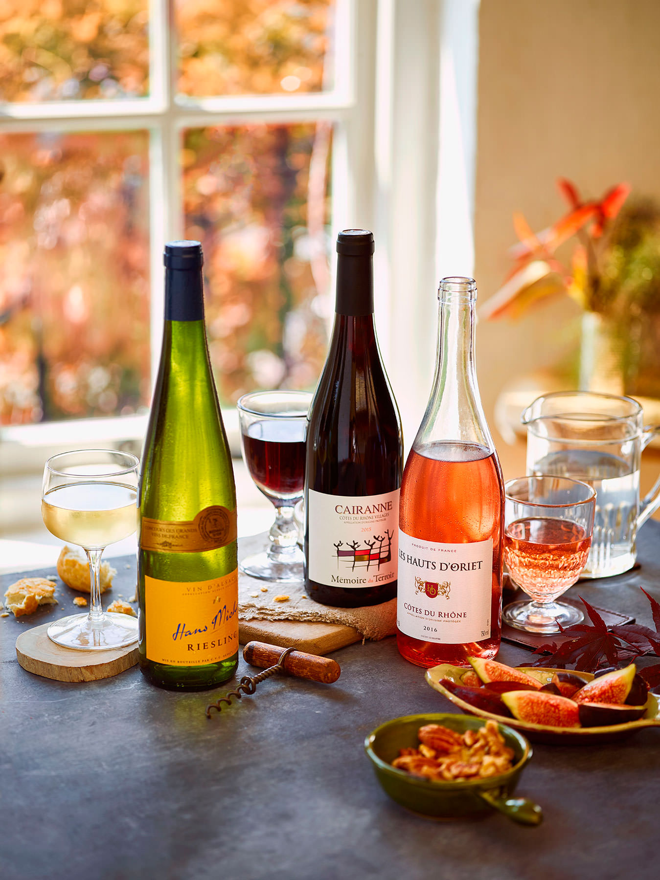 Bottles of wine arranged on a table with glasses with an autumnal setting - London Food & Drinks Photographer