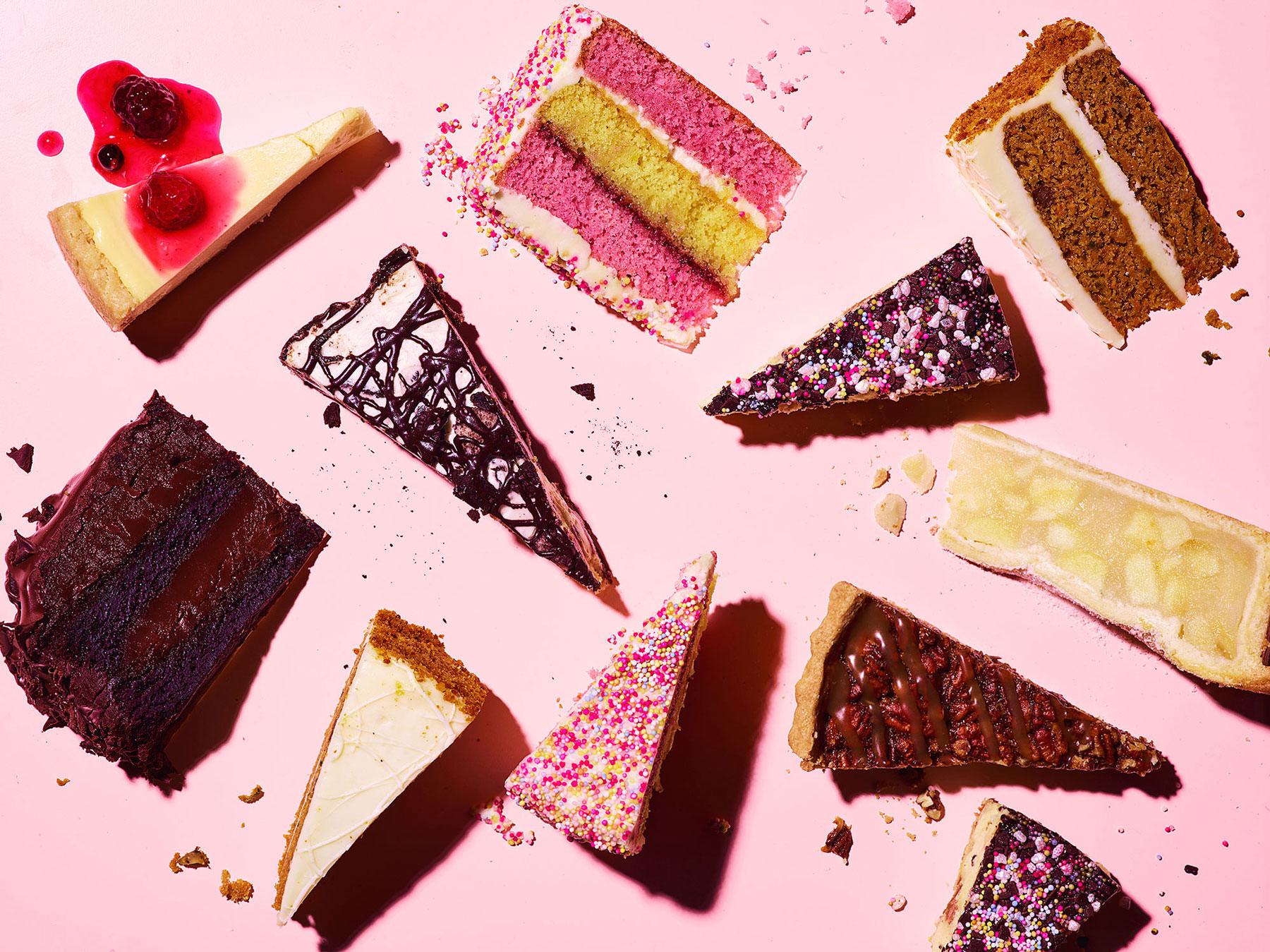 overhead shot of a selection of different slices of cake arranged graphically on a pink background  - London Food & Drinks Photographer