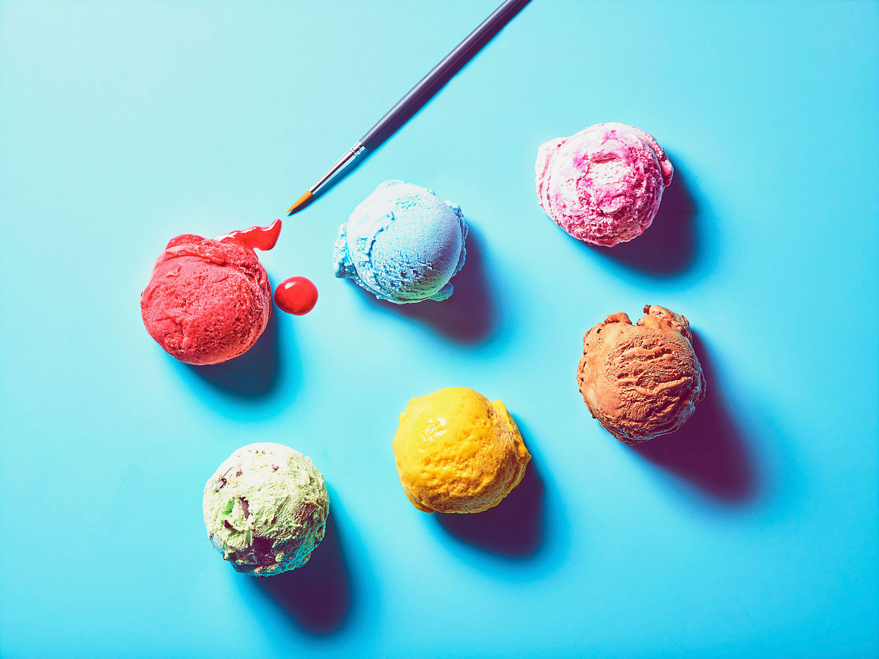 Flavoured gelato ice cream scoops placed on a bright blue background with a paintbrush - London Food & Drinks Photographer