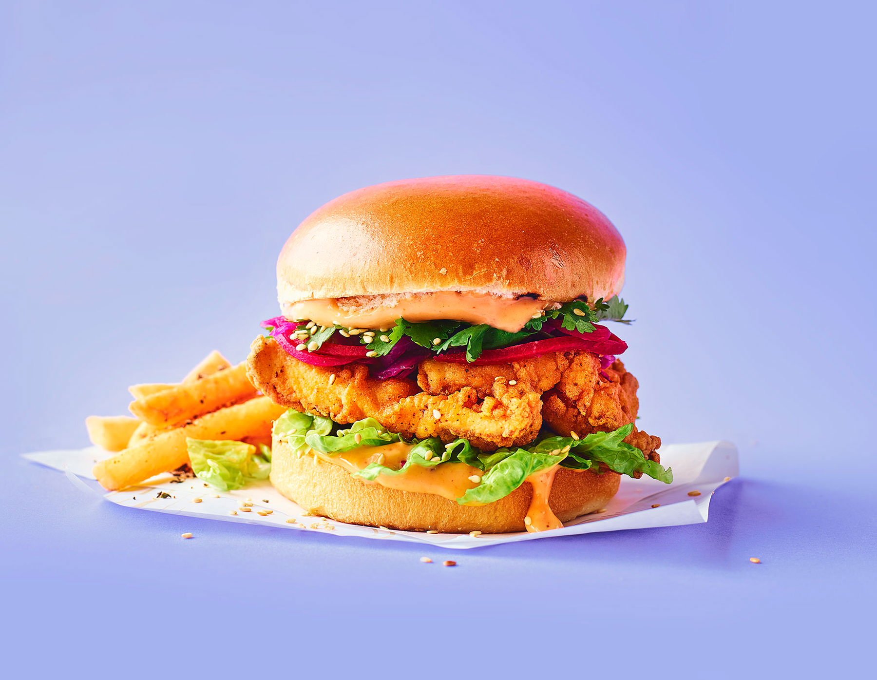 Korean Fried Chicken Burger served with chips, photographed on a lilac backdrop  - London Food & Drinks Photographer