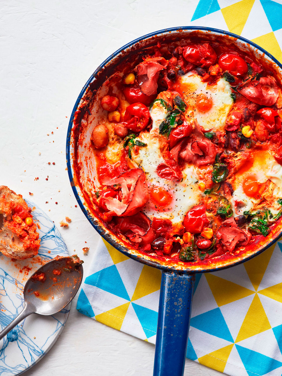 A pan filled with smoky bean and tomato baked eggs served with fresh crusty bread - London Food & Drinks Photographer