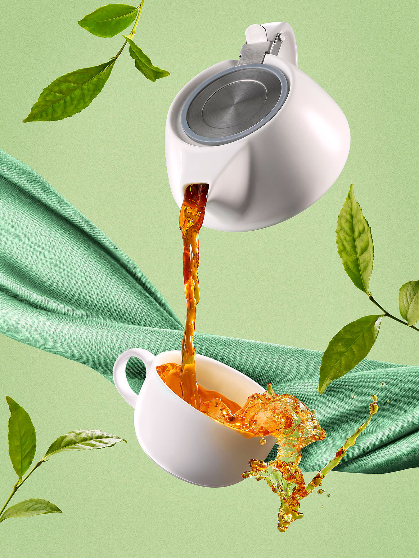 Tea pot pouring tea into a cup in mid air. Tea cup overflowing set on a green background - London Food & Drinks Photographer